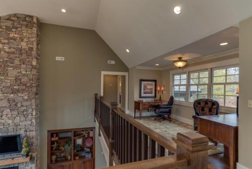 a living room with a staircase with a stone wall at Grand Family Retreat 8Br With Stunning Golf Views in Mill Spring