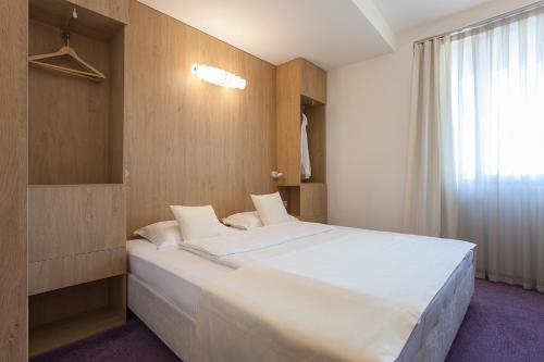a bedroom with a large white bed and a window at City Park Hotel in Skopje