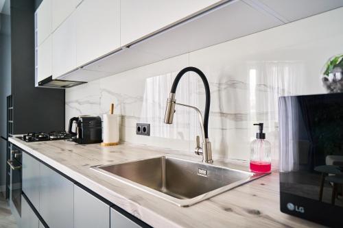 Una cocina con un fregadero con una botella de jabón rosa. en Full-Equipped 1BR in Center by Torro Mall, en Chişinău