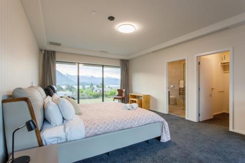 a bedroom with a bed and a large window at Grand Peninsula Lodge in Wanaka