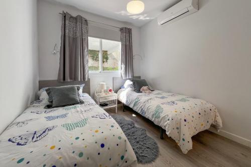a bedroom with two beds and a window at Relaxing Family Retreat with Stunning Golf Views in Benalmádena
