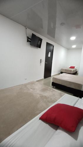 a bedroom with two beds and a red pillow at Hotel Blue in Santa Rosa de Cabal