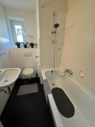 a bathroom with a tub and a toilet and a sink at Central Comfort Home with Garden in Meerbusch