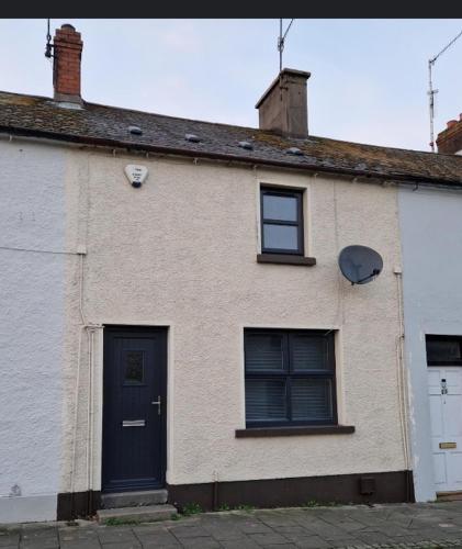a white house with a blue door and two windows at Fountain Street in Bessbrook