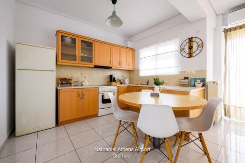 a kitchen with a wooden table and white appliances at Nathaniel Athens Airport in Spata