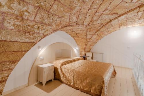 a bedroom with a bed and a stone wall at Corte Fontana in Ugento