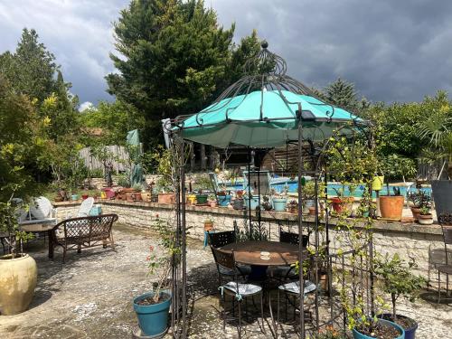 a table with an umbrella in a garden at LUBERON DES ARTISTES 2 in Apt