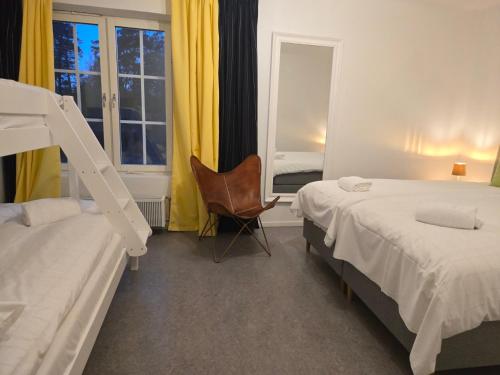 a bedroom with two beds and a chair and a window at Norrqvarn Hotel & Resort by Vänerport in Lyrestad