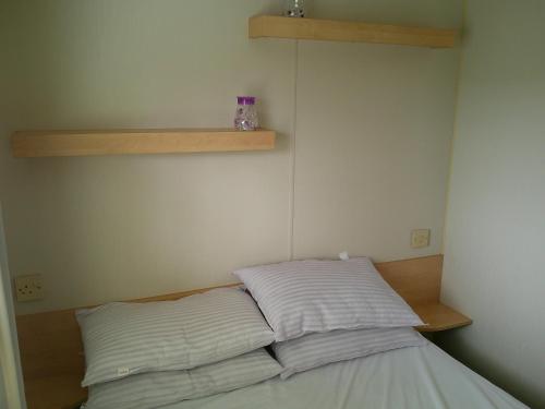 a bed in a room with two pillows on it at Promenade Vacation PR 8 Berth Access to the beach in Ingoldmells
