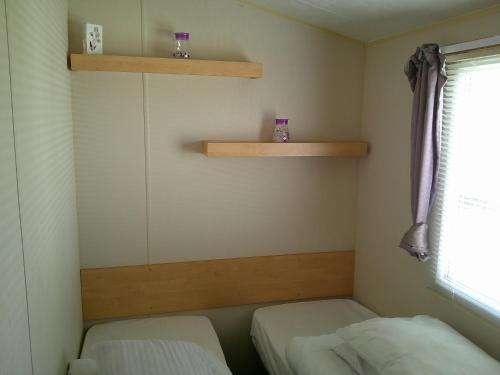 a small room with two beds and shelves at Promenade Vacation PR 8 Berth Access to the beach in Ingoldmells