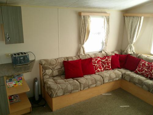 a living room with a couch with red pillows at Promenade Vacation PR 8 Berth Access to the beach in Ingoldmells