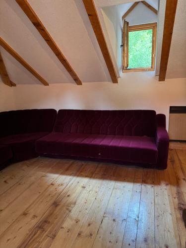 a purple couch in a room with a window at Kuća ispod Rajca in Slavkovica