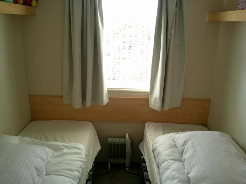 two beds in a room with a window at Promenade Vacation PR 8 Berth Access to the beach in Ingoldmells
