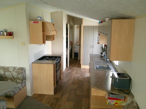 a small kitchen with a sink and a stove at Promenade Vacation PR 8 Berth Access to the beach in Ingoldmells