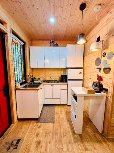 a kitchen with white cabinets and a wooden ceiling at WoodLand Tskhvarichamia in Tsʼkhvarichamia