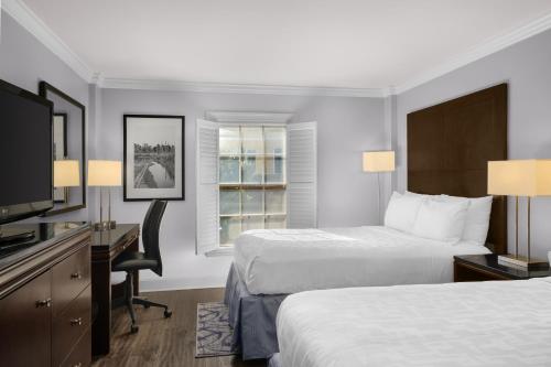 a hotel room with two beds and a desk and a television at Hotel Le Marais in New Orleans