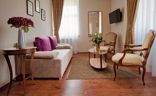 a living room with a couch and a table and chairs at Villa Patriot Apartmány in Mariánské Lázně