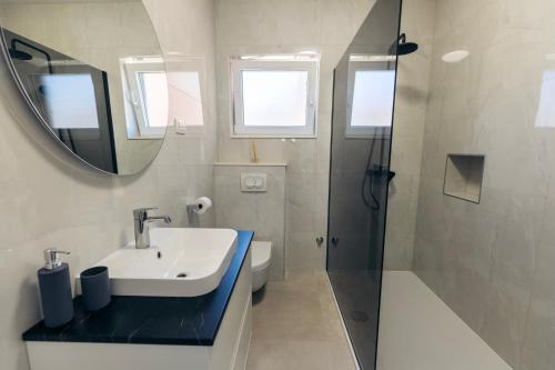 a bathroom with a sink and a mirror and a shower at Martha's Oliveyard in Biograd na Moru