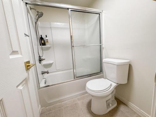 a white bathroom with a shower and a toilet at Family Retreat Near SLC Airport 6 BR 3 Bath in West Valley City