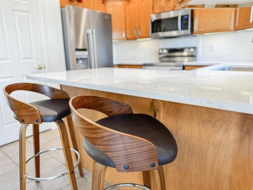 a kitchen with two bar stools at a counter at Family Retreat Near SLC Airport 6 BR 3 Bath in West Valley City