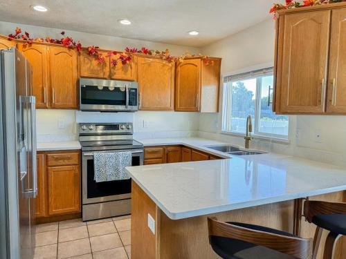 a kitchen with wooden cabinets and a stove top oven at Family Retreat Near SLC Airport 6 BR 3 Bath in West Valley City