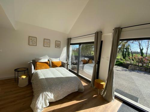 una camera da letto con un letto e una grande finestra di Lodge de Penfrat, une parenthèse en campagne aux portes de la ville a Quimper