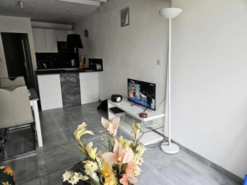 - un salon avec une télévision et une table fleurie dans l'établissement Résidence Héliovillage - VILLA T3 - 4 pers. CAP d'AGDE MAE-9611, au Cap d'Agde