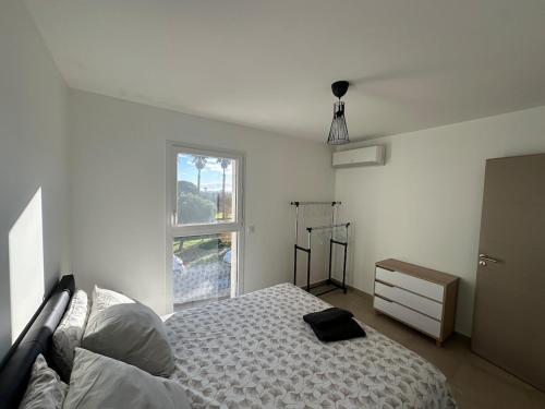 une chambre blanche avec un lit et une fenêtre dans l'établissement Villa Jasmin vue mer, à Sainte-Marie-la-Mer