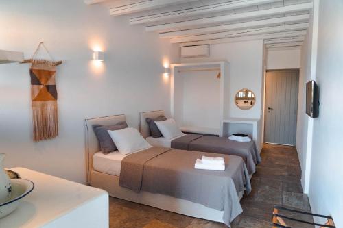 a hotel room with two beds and a table at Living Blue Tinos in Kardiani