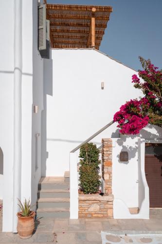 a white house with flowers on the stairs at Living Blue Tinos in Kardiani