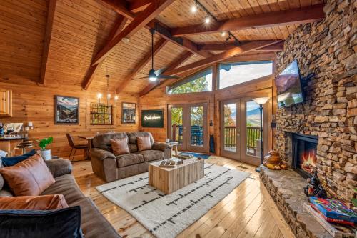 a living room with a fireplace and a stone wall at Mtn Views, Hot Tub, Sauna, EV, Arcade! in Gatlinburg