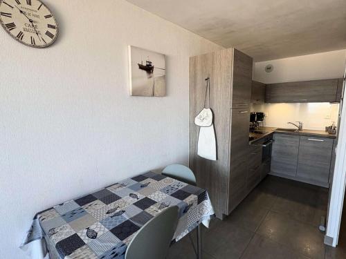 une cuisine avec une table et une horloge au mur dans l'établissement Résidence Les Océanes - Location de Vacances - PORNICHET - Studio cabine - Face Mer MAE-0651, à Pornichet