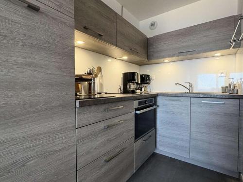 une cuisine avec des appareils en acier inoxydable et des armoires en bois dans l'établissement Résidence Les Océanes - Location de Vacances - PORNICHET - Studio cabine - Face Mer MAE-0651, à Pornichet