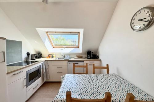une cuisine avec une table et une horloge au mur dans l'établissement Longère rénovée entre terre et mer 5min des plages, à Guidel