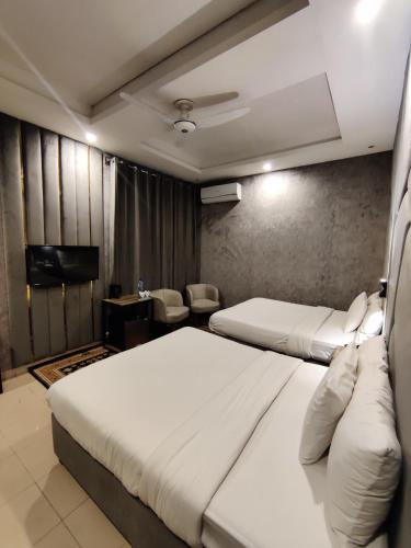 a hotel room with two beds and a flat screen tv at Shelton Boulevard Islamabad in Islamabad