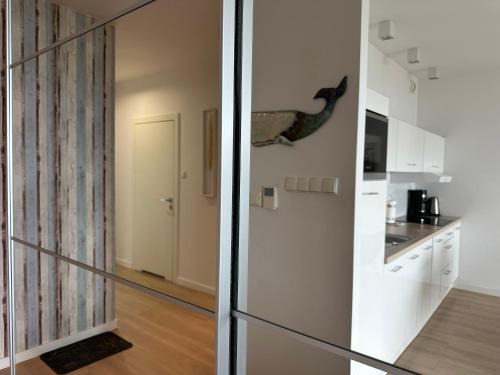 a kitchen with white cabinets and a glass door at FEWO Sea View East Tower Porta Mare in Dziwnówek