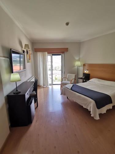 a bedroom with a bed and a desk and a television at Hotel Covilhã Jardim in Covilhã