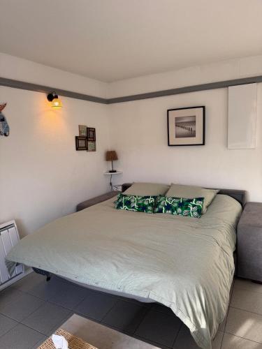 une chambre avec un grand lit avec des oreillers verts dans l'établissement Ocean and forest golf studio, à Moliets-et-Maa