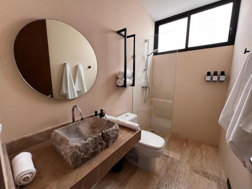 a bathroom with a sink and a toilet and a mirror at Penthouse Om in Tulum