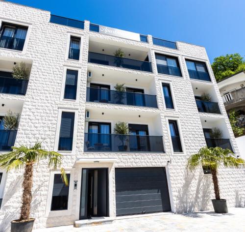 an apartment building with palm trees in front of it at Apartments Ivo Herceg Novi in Herceg-Novi