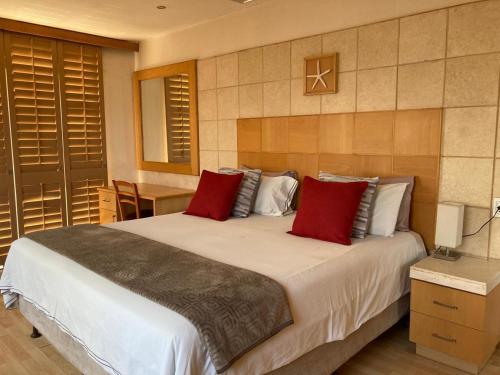a bedroom with a large bed with red pillows at Calypso Beach Holiday House in Langebaan
