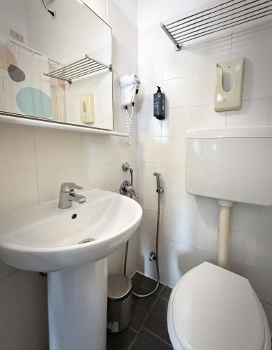 a white bathroom with a toilet and a sink at Hotel Meublè Agavi in Monterosso al Mare
