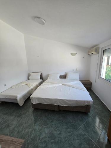 two beds in a room with white walls and a window at SHARRI Apartments in Ulcinj