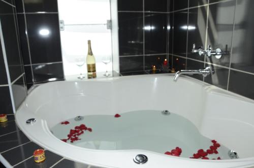 a bath tub with red flowers around it in a bathroom at Aqua Hotel Cusco in Cusco