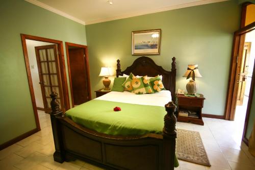 a bedroom with a large bed with green walls at Rayon Hotel in Negril