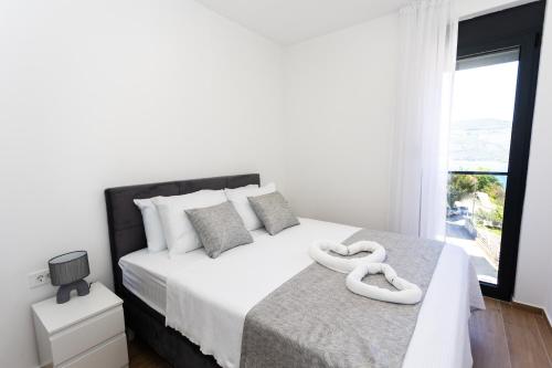 a white bedroom with a large bed with white pillows at Apartments Ivo Herceg Novi in Herceg-Novi