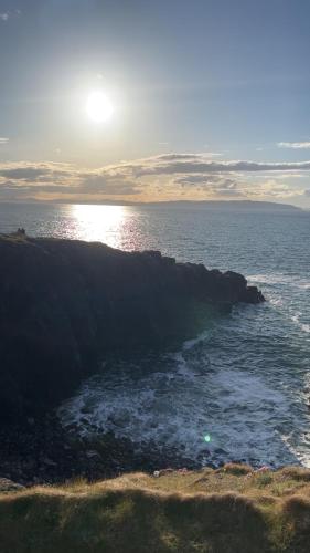 a view of the ocean with the sun setting on a cliff at Atlantic Port Retreat in Portstewart