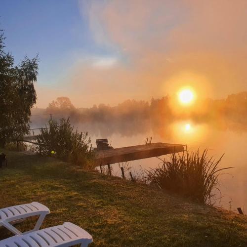 a misty sunrise over a lake with a dock at Перлина Буковини in Lipovany