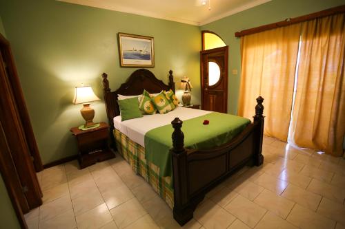 a bedroom with a large bed with green walls at Rayon Hotel in Negril