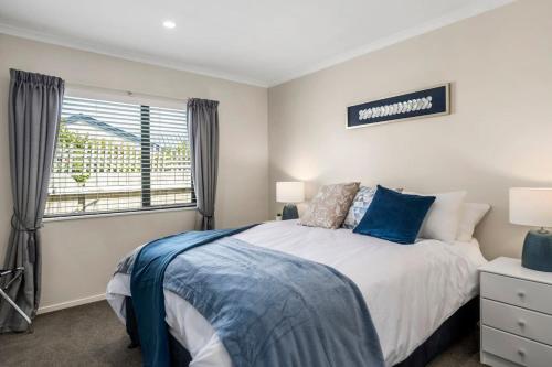 a bedroom with a bed and a window at Logan House, Stylish Getaway With BBQ and Yard in Taupo